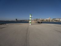 this is an ocean front with the town in the background and a road sign on the end of the walkway