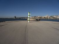 this is an ocean front with the town in the background and a road sign on the end of the walkway