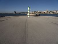 this is an ocean front with the town in the background and a road sign on the end of the walkway