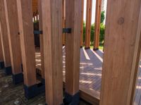 an outdoor toilet made out of wood and metal bars near the pool area of a home