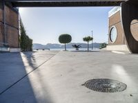 a cement walkway that leads into a parking garage with two trees and a large potted tree