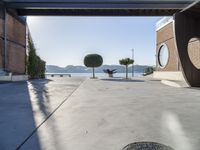 a cement walkway that leads into a parking garage with two trees and a large potted tree