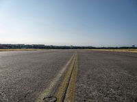 a street next to an airport on a sunny day and blue skies above the ground