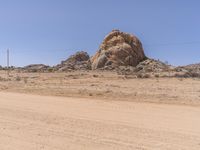 a truck driving through the desert with large rocks in the background of it and power lines