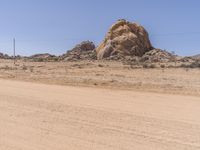 a truck driving through the desert with large rocks in the background of it and power lines