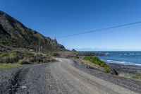 a gravel road going past the ocean on the edge of a cliff face at low tide