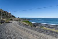 a gravel road going past the ocean on the edge of a cliff face at low tide