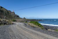 a gravel road going past the ocean on the edge of a cliff face at low tide