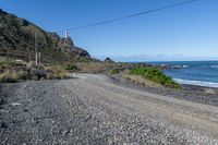 a gravel road going past the ocean on the edge of a cliff face at low tide