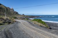 a gravel road going past the ocean on the edge of a cliff face at low tide