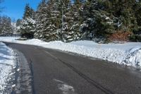 the corner of a snowy street with many evergreen trees, and many snow - covered roads