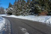 the corner of a snowy street with many evergreen trees, and many snow - covered roads