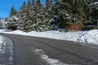 the corner of a snowy street with many evergreen trees, and many snow - covered roads