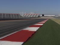 an empty track at a motorsports club with some red and white stripeing on it