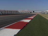 an empty track at a motorsports club with some red and white stripeing on it