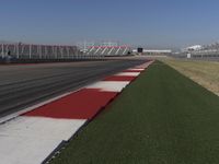 an empty track at a motorsports club with some red and white stripeing on it