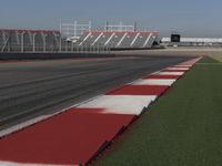 an empty track at a motorsports club with some red and white stripeing on it