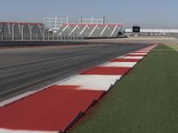 an empty track at a motorsports club with some red and white stripeing on it