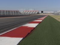 an empty track at a motorsports club with some red and white stripeing on it