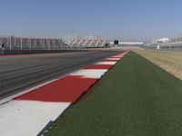 an empty track at a motorsports club with some red and white stripeing on it