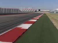 an empty track at a motorsports club with some red and white stripeing on it