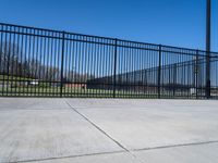 a cement floor area with an empty lot behind it and a fence surrounding the park