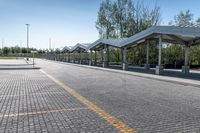 a paved street with parking lots in between two rows of benches and several trees around it