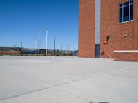 a fire hydrant on a concrete driveway near a tall building with a blue sky in the background