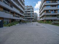 a skateboarder riding through the middle of an open concrete courtyard with buildings in the background