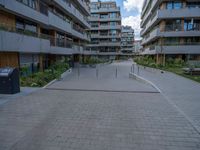 a skateboarder riding through the middle of an open concrete courtyard with buildings in the background