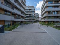 a skateboarder riding through the middle of an open concrete courtyard with buildings in the background