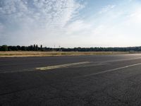 a road next to a lot with a plane sitting on it's side and grass in the background