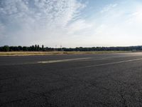 a road next to a lot with a plane sitting on it's side and grass in the background