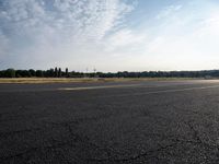 a road next to a lot with a plane sitting on it's side and grass in the background