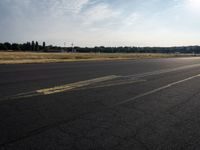 a road next to a lot with a plane sitting on it's side and grass in the background