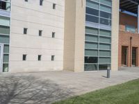 the shadow of a clock on the sidewalk is seen in front of the building that is next to the grass