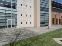 the shadow of a clock on the sidewalk is seen in front of the building that is next to the grass