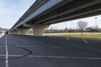 an empty parking lot with cars driving under an overpass or abovepass of the highway