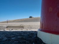 two people walking next to a lighthouse on a beach with a ramp leading to it