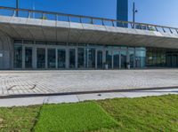 an empty red fire hydrant in front of a large building with glass doors and walkway