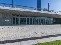 an empty red fire hydrant in front of a large building with glass doors and walkway