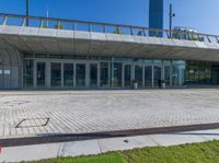 an empty red fire hydrant in front of a large building with glass doors and walkway