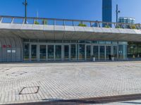 an empty red fire hydrant in front of a large building with glass doors and walkway