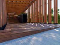 a walkway with wooden poles and a bench underneath them on a sunny day in a park