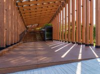 a walkway with wooden poles and a bench underneath them on a sunny day in a park