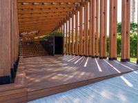 a walkway with wooden poles and a bench underneath them on a sunny day in a park