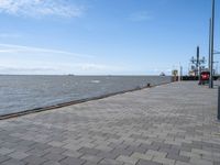 a view of the water and a dock on a large body of water from a walkway with brick walkway