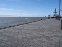 a view of the water and a dock on a large body of water from a walkway with brick walkway