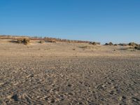 a sandy beach with footprints of people on the sand in the background and a fence separating the beach