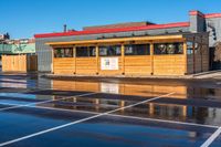 a wet car parking lot full of a small wooden building with a sign attached to it's roof